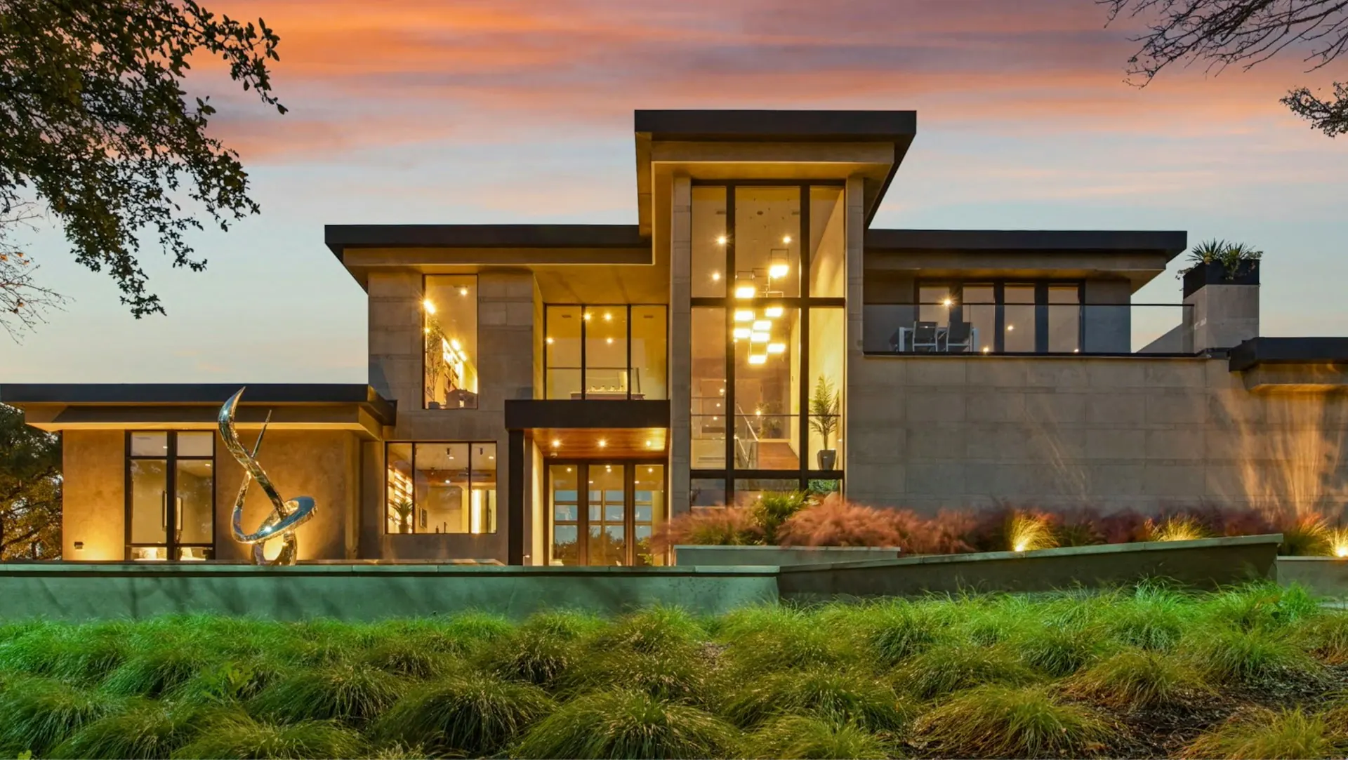 A modern home at dusk, every window glowing warm against the evening sky